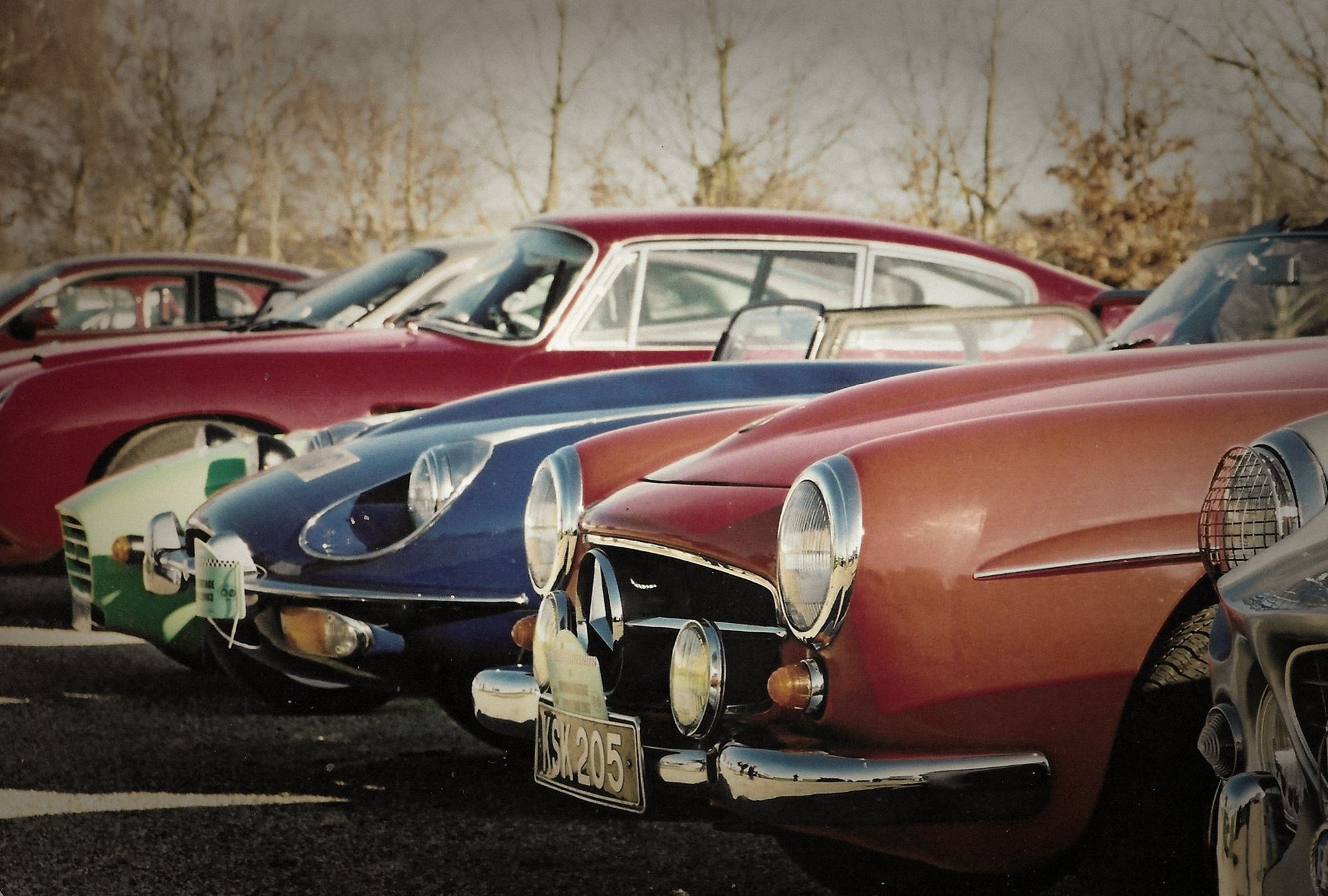 Classic sports cars lined up nose to nose in low winter sun